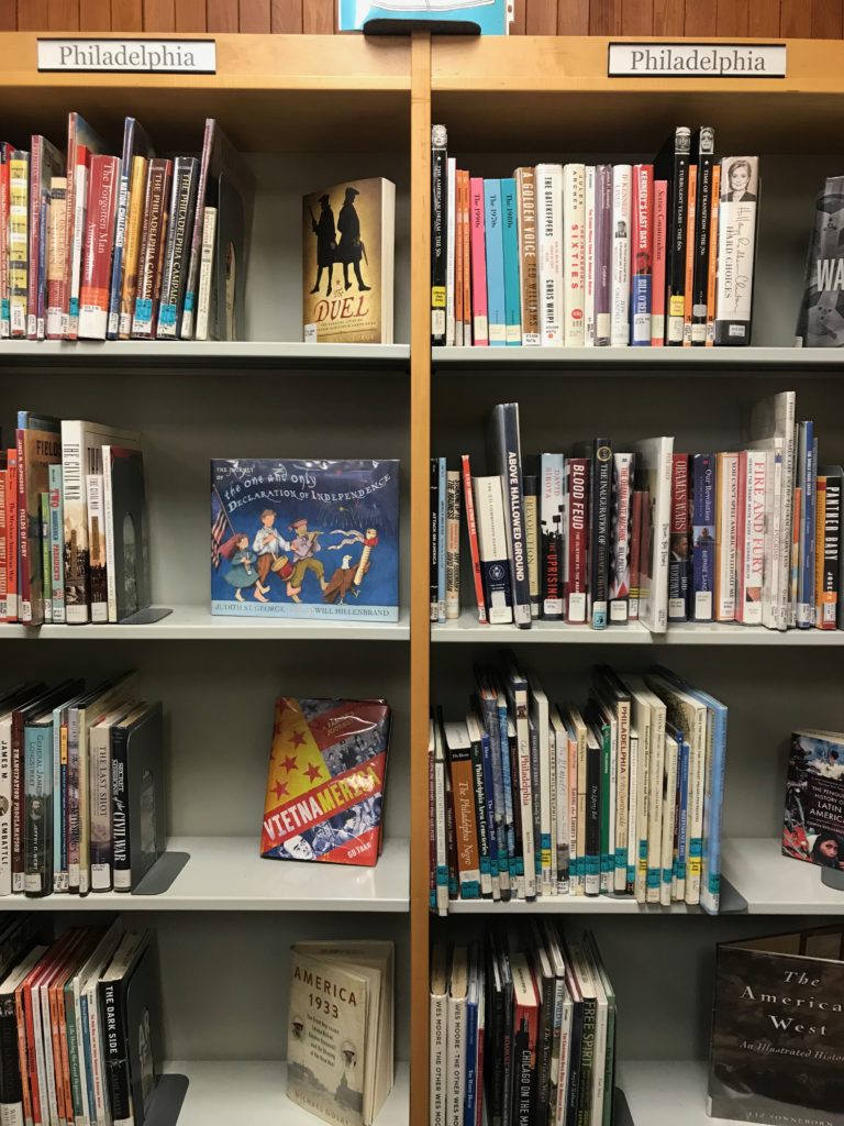 8 shelves of books, with one book turned out for display on each shelf